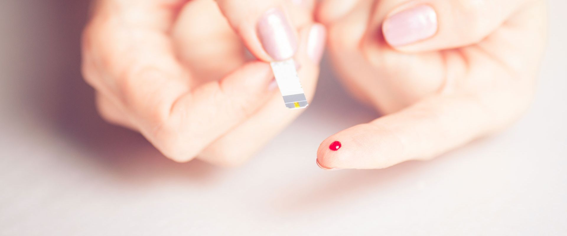 Finger mit Bluttropfen und Teststreifen