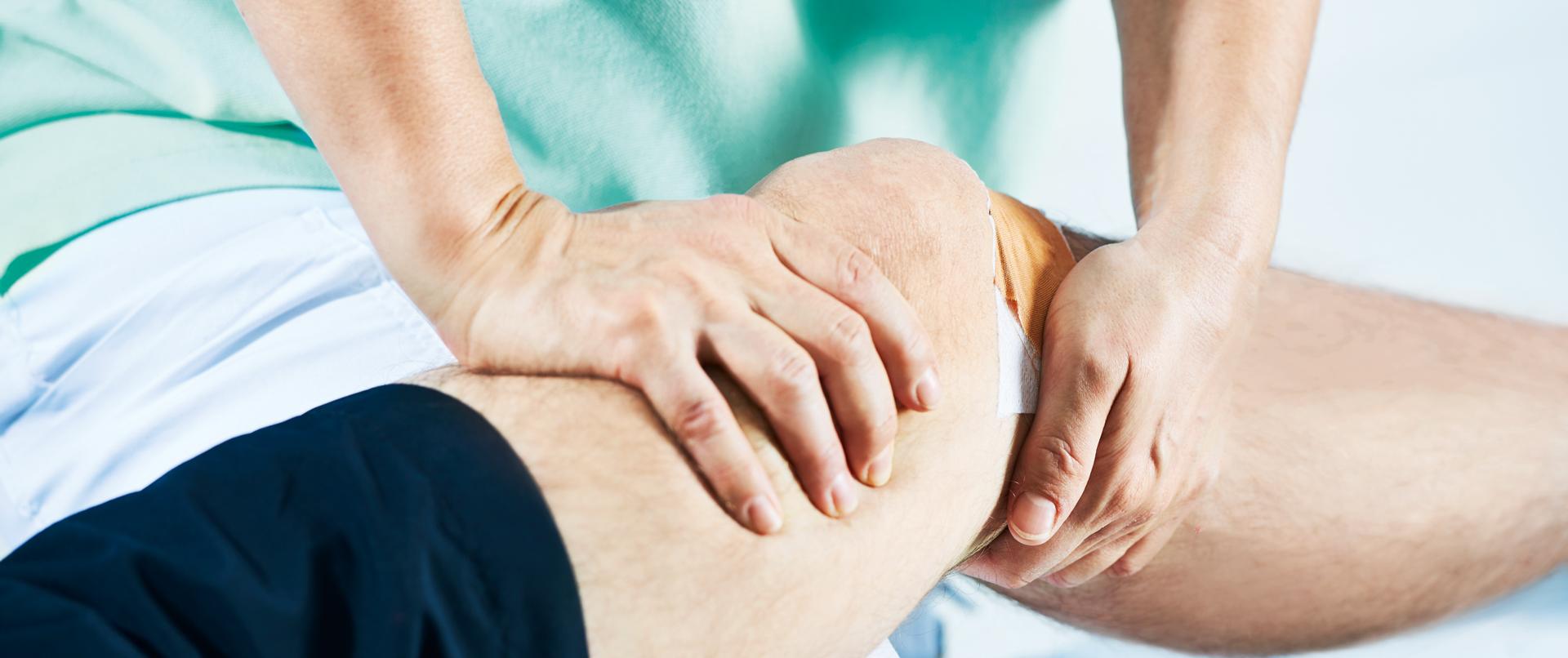 Physiotherapeutin behandelt Knie eines Patienten