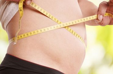 Person hält Meter um ihren Bauch