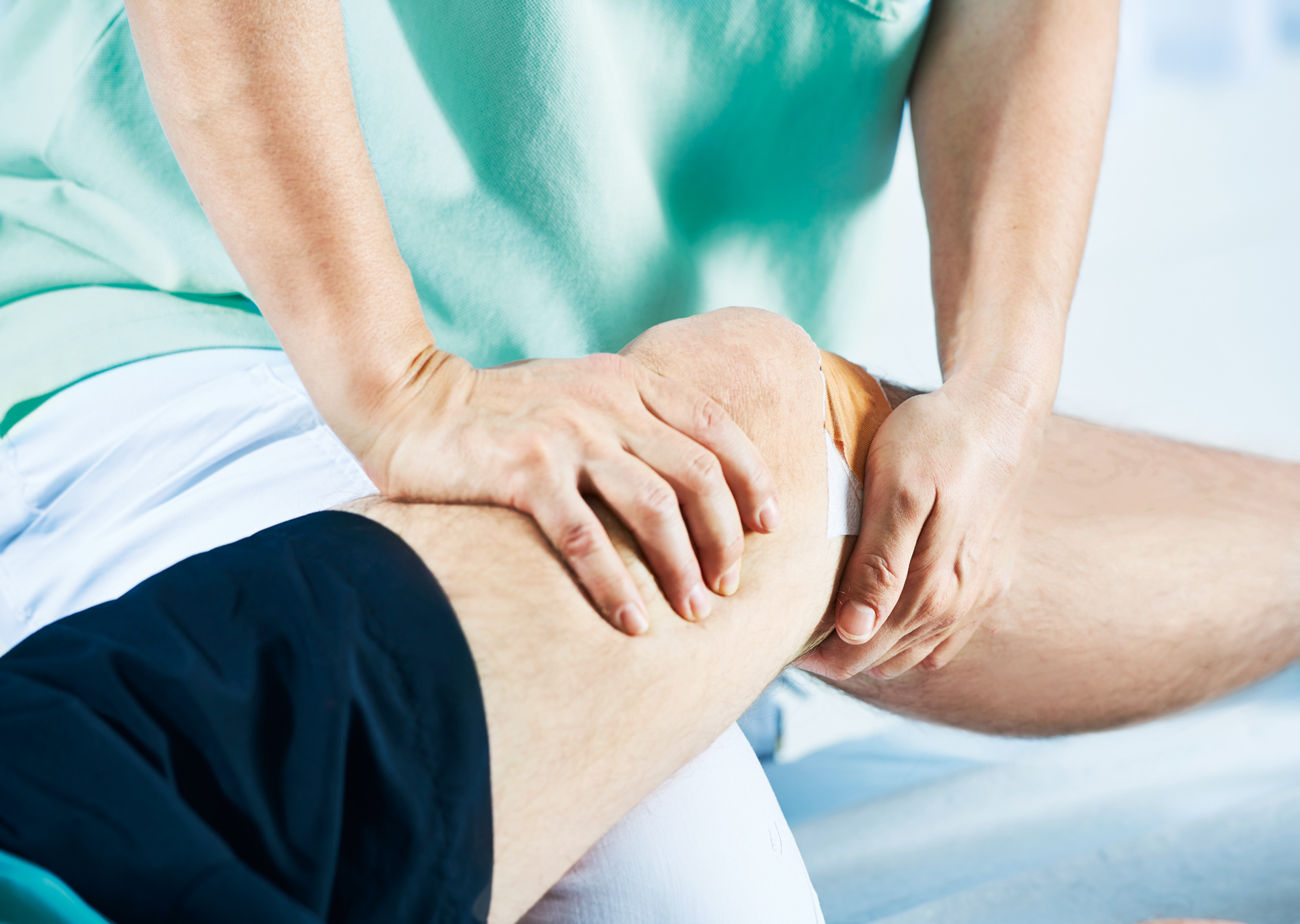 Physiotherapeutin behandelt Knie eines Patienten Physiotherapeutin behandelt Knie eines Patienten